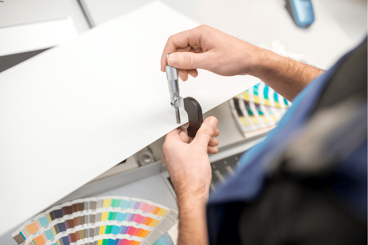 Engineer measuring material thickness and checking Pantone colors for flexible packaging quality