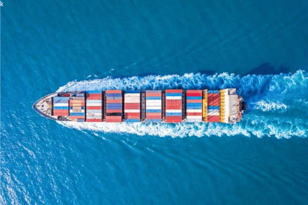 Aerial view of a cargo ship carrying colorful containers across the sea, illustrating the importance of packaging durability during ocean shipping.