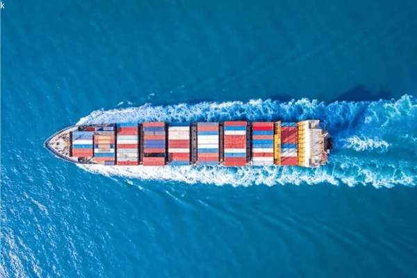 Aerial view of a cargo ship carrying colorful containers across the sea, illustrating the importance of packaging durability during ocean shipping.