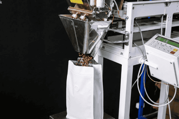 Coffee stand up pouch with one-way degassing valve being filled on an automated packaging line, showing compatibility with vertical filling equipment.