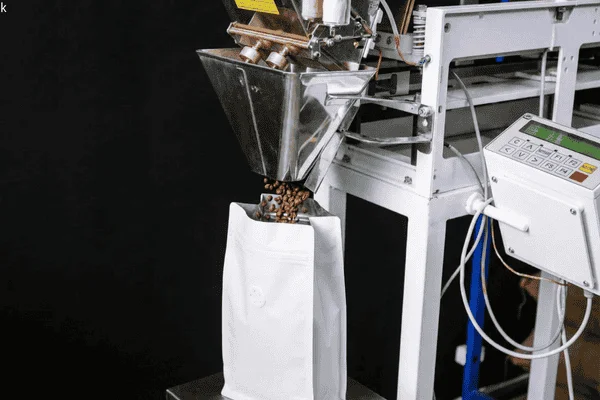 Coffee stand up pouch with one-way degassing valve being filled on an automated packaging line, showing compatibility with vertical filling equipment.